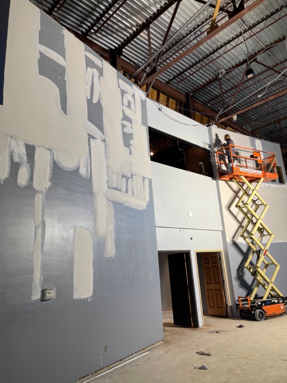 Commercial drywall contractor in Houston, TX floating a high wall from a scissor lift