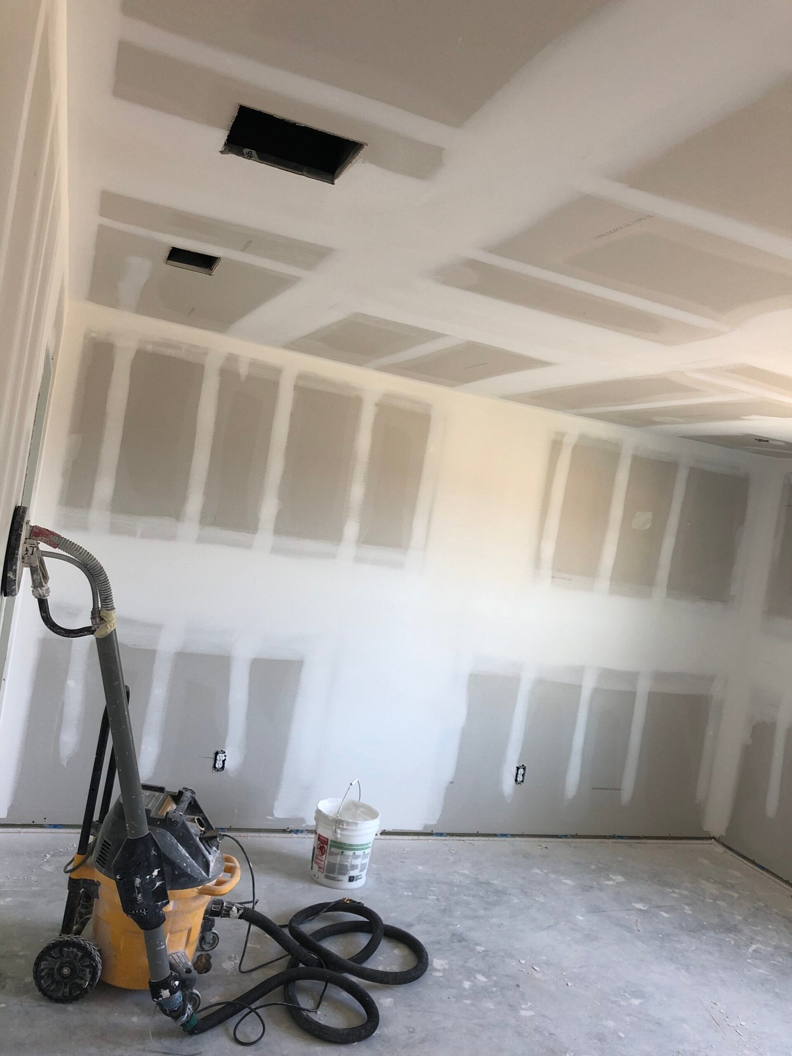 Drywall contractor in Houston, TX finishing a ceiling and taped walls after a three-coat float